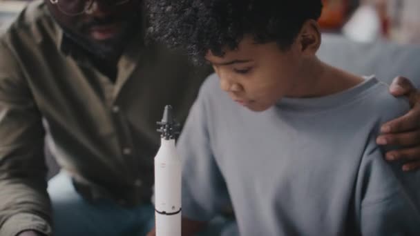 Сосредоточить Ручной Снимок Афроамериканского Отца Поддерживающего Маленького Сына Строит Ракету — стоковое видео