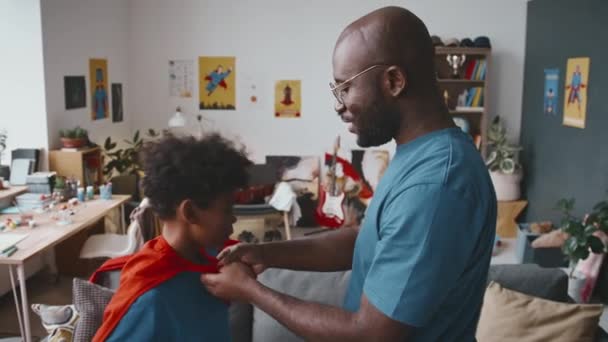 Счастливый Маленький Афроамериканец Костюме Супергероя Бегает Гостиной Играет Веселым Отцом — стоковое видео