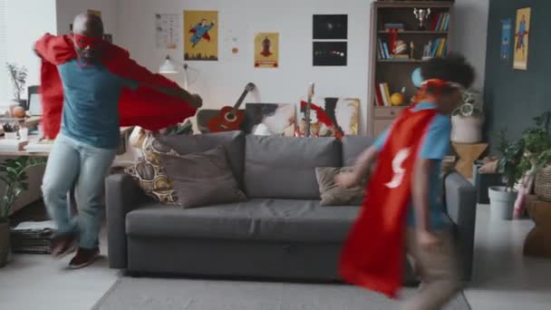 Afro Amerikaanse Vader Opgewonden Zoontje Superheldenkostuums Die Samen Door Woonkamer — Stockvideo