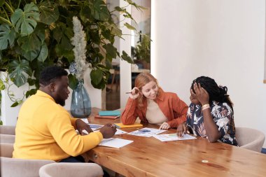 Üç farklı iş adamından oluşan bir grup şık günlük kıyafetler giyip restoranda oturmuş projenin tadını çıkarıyorlar.