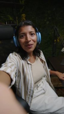 Kadın blogcunun podcast stüdyosunda sosyal medya için video çekerken kamerada konuştuğu ve misafiri tanıttığı dikey çekim