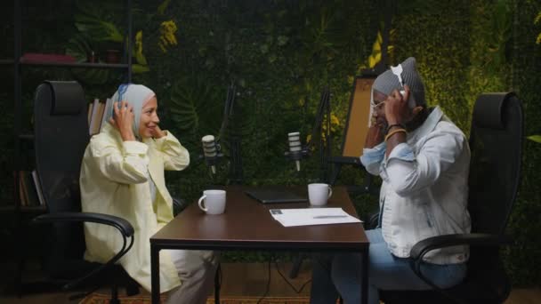 Widok Boku Afroamerykańskiego Gospodarza Podcastu Kobiety Hidżabie Zakładającej Słuchawki Przygotowującej — Wideo stockowe