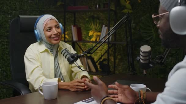 Přes Rameno Pohled Veselou Ženu Hidžábu Sluchátka Úsměvem Mluvení Mikrofonu — Stock video