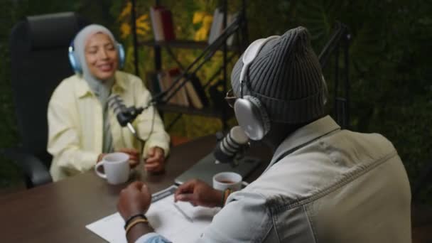 Musta Podcast Isäntä Kuulokkeet Puhuu Mikrofonilla Haastattelemalla Nuori Nainen Hijabissa — kuvapankkivideo