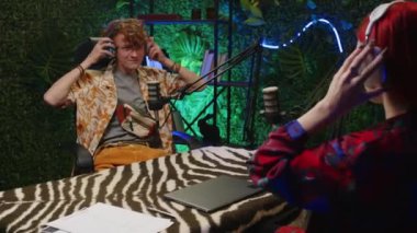 Genç Gen Z blogcusu ve kadın sunucusu kulaklık takıp mikrofonla konuşurken aynı zamanda moda stüdyosunda podcast yapmaya başlıyorlar.