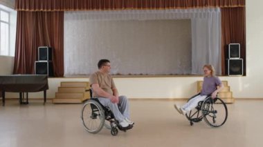 Tekerlekli sandalyedeki kadın ve erkeğin resitalde toplanıp dans dersinden önce konuştuğu geniş açı.