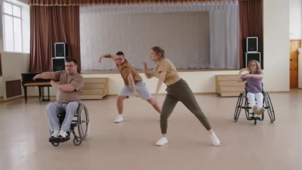 坐在轮椅上的男女青年在演奏厅练习时 与两名专业编舞师一起表演当代表现力十足的舞蹈 — 图库视频影像