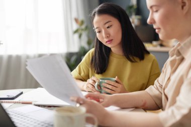 Evde oturmuş sınava hazırlanan iki farklı üniversite öğrencisinin seçmeli odak noktası.
