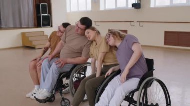 Tekerlekli sandalyedeki kadın ve erkek dans ekibiyle provalarda eğleniyorlar. Hareketleri prova ediyorlar, müzik dinliyorlar ve stüdyoda şarkı söylüyorlar.