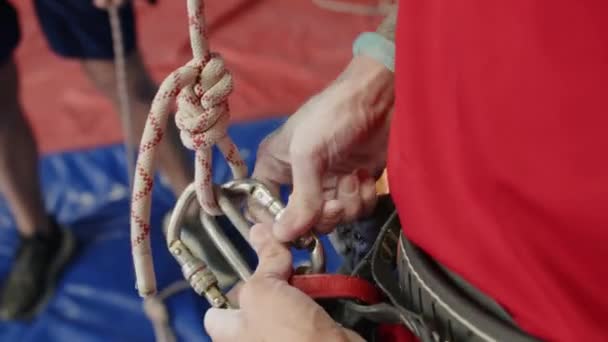 クライミングジムでハーネスにロープを付けながら 認識できない男の手のクローズアップショット — ストック動画