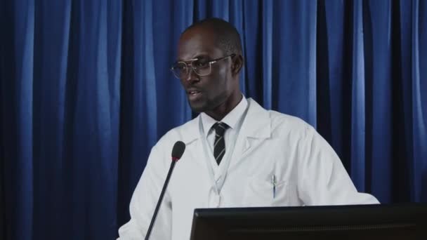 Młody Czarny Urzędnik Służby Zdrowia Płaszczu Medycznym Stojący Scenie Lectern — Wideo stockowe