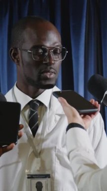Basın toplantısı sırasında TV muhabirlerine röportaj verirken Afrikalı Amerikalı sağlık liderinin mikrofonla konuştuğu dikey çekim