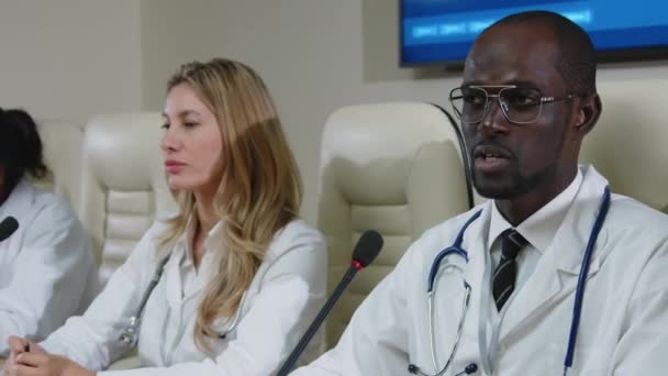 Médico Negro Con Abrigo Médico Sentado Con Comité Mesa Conferencia — Vídeo de stock