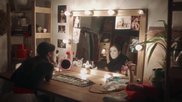 책상에 Illuminiated 거울에서 어두운 드레싱 룸에서 공연을 메이크업을 여배우 — 비디오