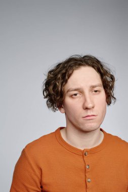 Kameraya ilgisiz yüz ifadesi ile genç beyaz tenli birinin dikey yakın çekim stüdyo portresi, kopyalama alanı