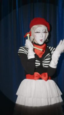 Dişi pandomim sanatçısının telefon olarak çiçek oyuncağını kullanması, telefonla konuşması ve sahnede komedi gösterisi yapması.