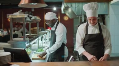 Afro-Amerikalı ve Kafkas şefler yemek malzemelerini kesiyorlar ve iş günü birlikte yemek pişiriyorlar.