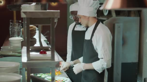 Joven Chef Masculino Caucásico Cocinando Comida Hablando Con Compañero Trabajo — Vídeo de stock
