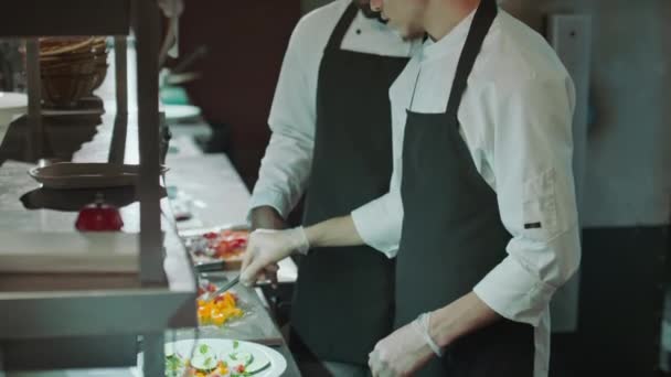 料理にグルメを追加し レストランキッチンで食べ物を提供する方法を教えるシェフ — ストック動画