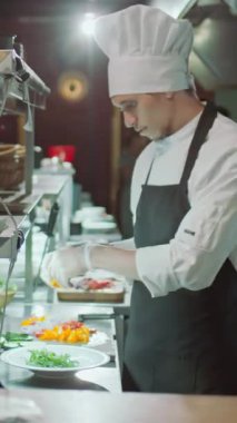 Önlüklü ve eldivenli profesyonel bir aşçının restoranda sipariş verirken tabakta servis yaptığı dikey pozlar.