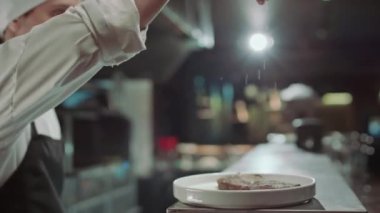 Aşçıbaşı et bifteğine tuz ve biber eklerken restoranın mutfağında yemek hazırlıyor.