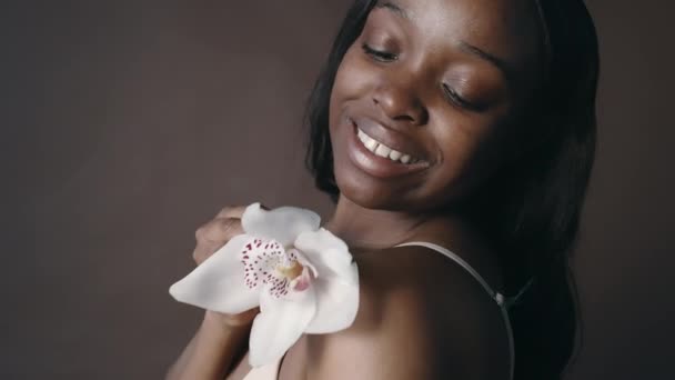 아프리카계 미국인 꽃으로 그녀의 피부를 만지고 스튜디오에서 카메라를 포즈하면서 냄새와 — 비디오