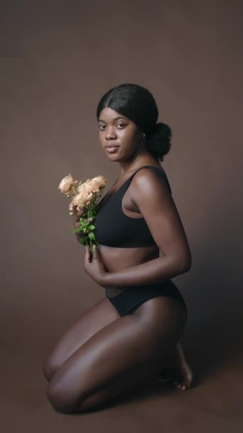 Pionowe Ujęcie Pięknej Czarnej Dziewczyny Minimalistycznej Bieliźnie Siedzącej Podłodze Studio — Wideo stockowe