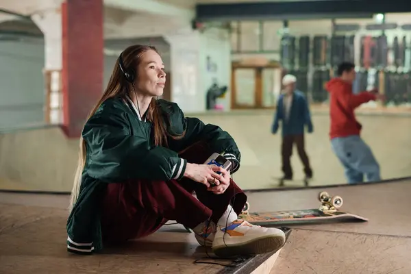 Moderna Chica Caucásica Sentada Suelo Skatepark Sosteniendo Reproductor Audio Portátil Fotos de stock libres de derechos