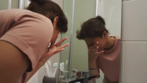 욕실에서 싱크대 그녀의 얼굴을 집에서 아침에 불편하고 느끼는 거울에서보고 — 비디오