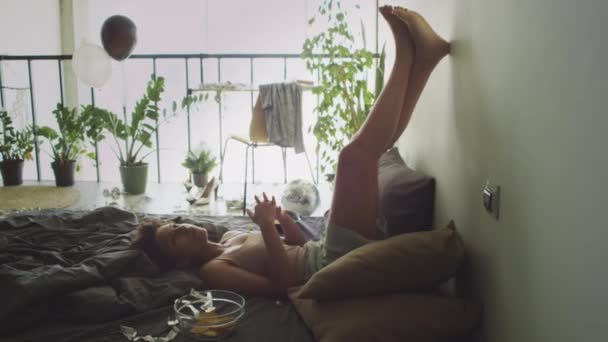 Lelah Gadis Berbaring Tempat Tidur Berantakan Dengan Kaki Dinding Dan — Stok Video