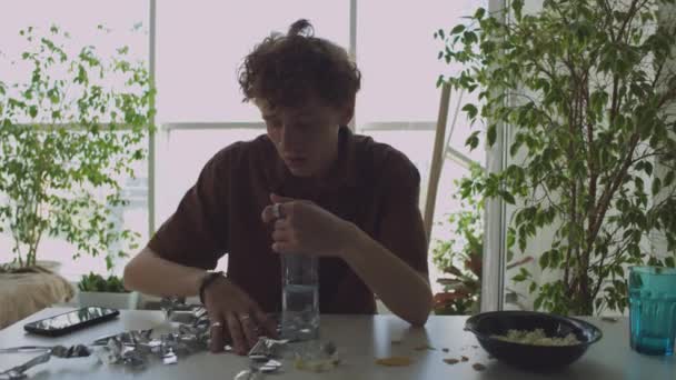 Ung Baksmälla Man Sopa Tinsel Från Bordet Dricka Vatten Från — Stockvideo