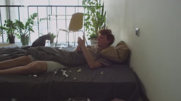 Young Hungover Guy Waking Messy Bed Checking Mobile Phone Yawning — Stock Video
