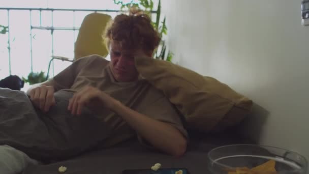 Молодой Больной Человек Просыпается Грязной Постели Разбросанными Закусками Выключает Сигнализацию — стоковое видео