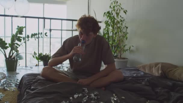 Νεαρός Μεθυσμένος Τύπος Κάθεται Βρώμικο Κρεβάτι Στο Σπίτι Πίνοντας Νερό — Αρχείο Βίντεο