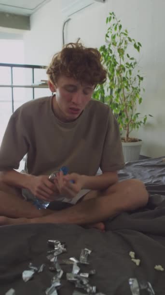 Vertical Portrait Shot Young Hungover Man Sitting Unmade Bed Tinsel — Stockvideo