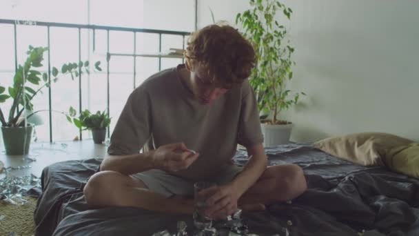 남자가 유리에 정제를 마시는 만들지 지저분한 침대에 앉아서 아침에 숙취로 — 비디오