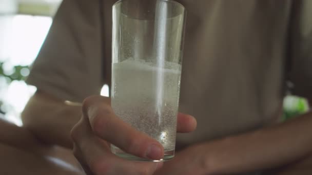 水のガラスを保持するハンガーホールドに苦しんでいる認識できない男の手の近くのビュー 発熱タブレット — ストック動画