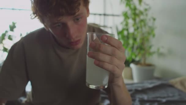 Νεαρός Τύπος Hungover Κοιτάζοντας Ένα Ποτήρι Νερό Αναβράζον Δισκίο Διαλύεται — Αρχείο Βίντεο