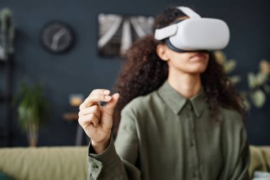 VR kulaklık kullanırken uzun kıvırcık saçlı, tanınmayan genç bir kadının seçmeli odak noktası.