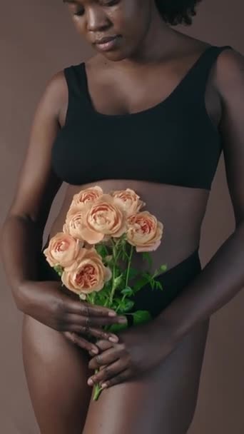 Pionowe Ujęcie Afroamerykanki Czarnej Bieliźnie Trzymającej Bukiet Róż Podczas Pozowania — Wideo stockowe
