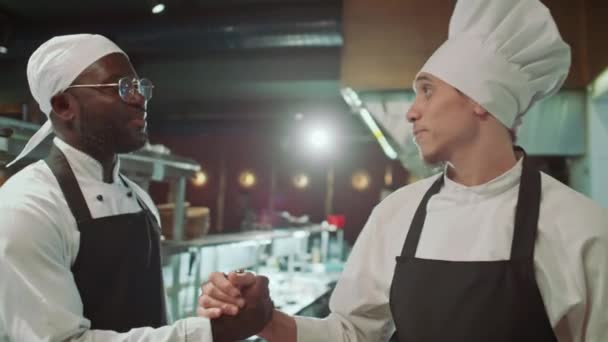 Junger Kaukasischer Koch Schürze Und Hut Begrüßt Schwarzen Mitarbeiter Mit — Stockvideo
