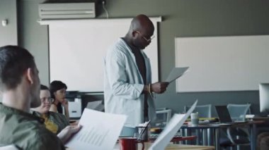 Tekerlekli sandalyede oturan genç adam, Afrika kökenli Amerikalı yöneticiyi selamlıyor ve iş günü onunla konuşuyor.