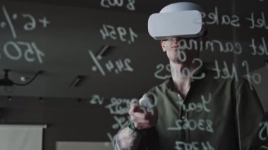 BT şirketinin ofisinde yeni uygulamayı test ederken VR kulaklık takan adamın formüllerinin yazılı olduğu cam duvardan bak