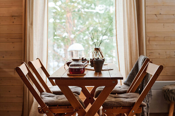 No people shot of teapot, mug and vase on wooden dining table in modern cottage interior, copy space