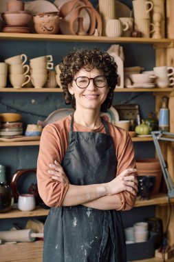 Çömlek atölyesinde çalışan kolları bağlı neşeli, beyaz kadın portresi.