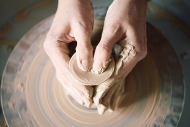 Yukarıdan bakıldığında, çömlekçi çarkında kil şekillendiren tanınmayan zanaatkarların elleri görünüyor.