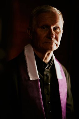 Kameraya bakan Kafkasyalı Katolik rahibin dikey, orta boy, yakın plan portresi.