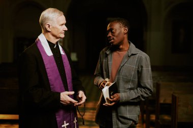 Kafkasyalı Katolik rahip ve Afrikalı Amerikalı kilise cemaatinin dini metinleri tartışırken orta boy fotoğrafı.