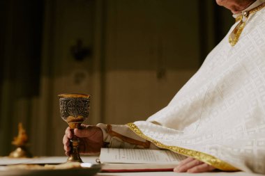 Tanınmayan Katolik rahibin kutsal ayin için şarap bardağını mihraba koyması, boşluğu kopyalaması...