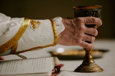Katolik kilisesinde mihrabın önünde dikilmiş şarap içen tanınmayan kıdemli rahibin kırışık eli.